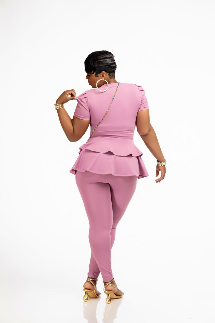 Woman wearing a pink Pooh Wear Work to Workout top , peplum skirt and leggings set on a white background