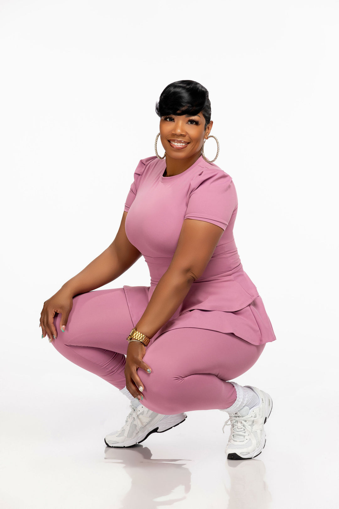 Woman wearing a pink Pooh Wear Work to Workout top , peplum skirt and leggings set on a white background