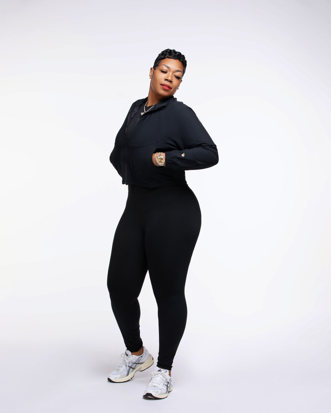 Person wearing a black outfit with white sneakers on a white background