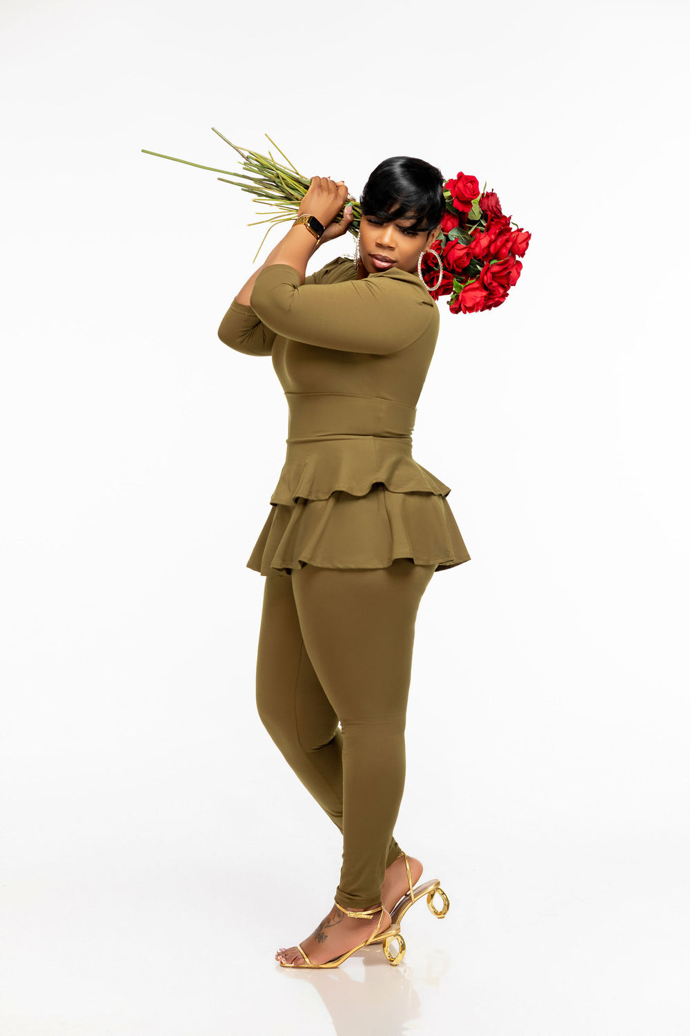 Woman in a green Pooh Wear Work to Workout three piece athletic outfit holding red roses against a white background